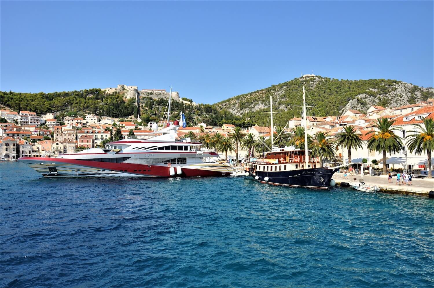 Yachts moored alongside palm lined promenade, Hvar