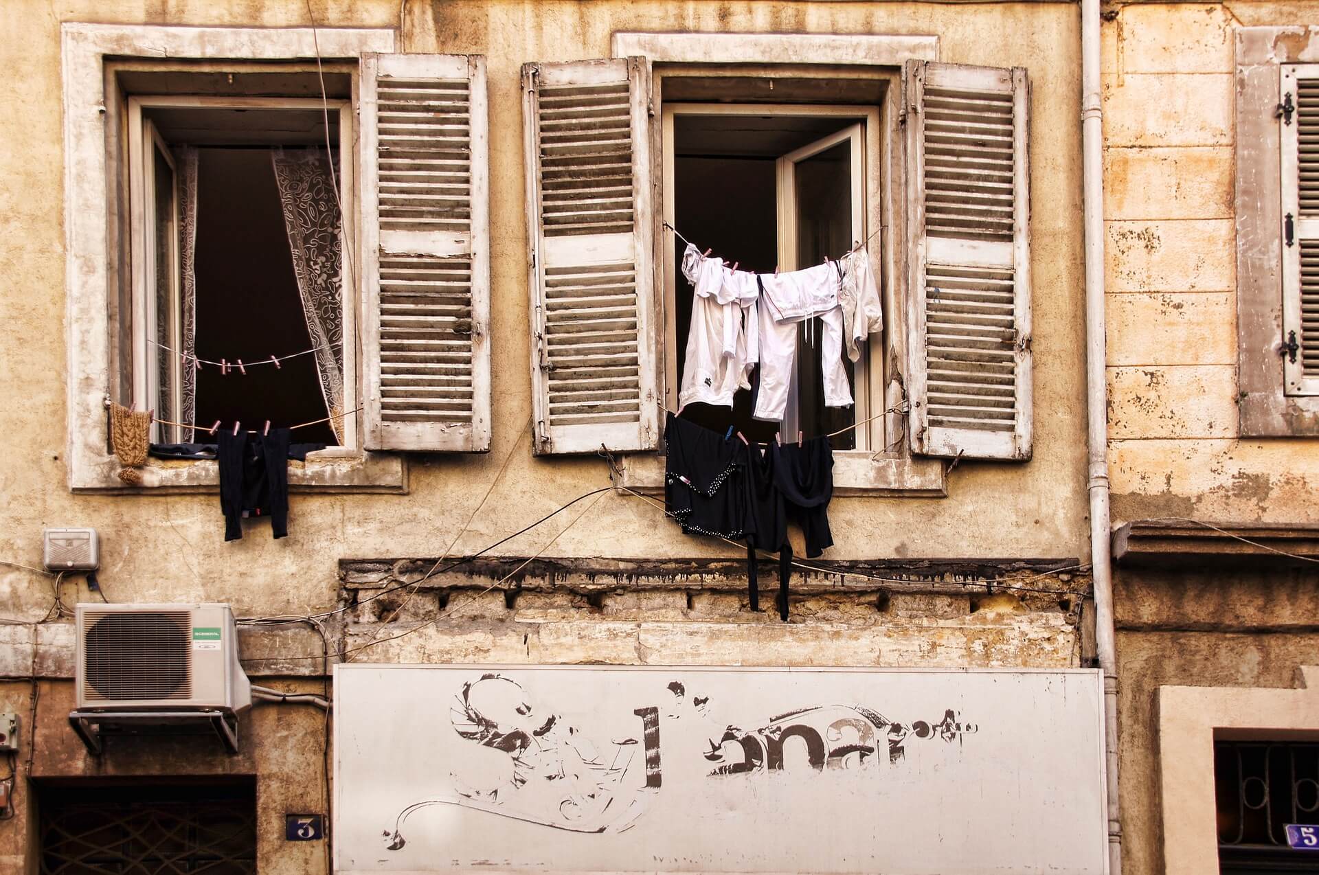 Washing hanging in the windows of a stone building with open shutters