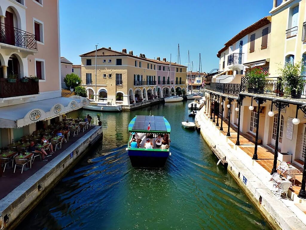 Boat cruises along canal lined with buildings in Port Grimaud